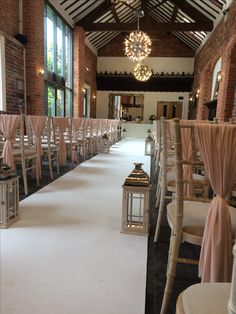 an empty hall with rows of chairs and chandeliers on either side of the aisle