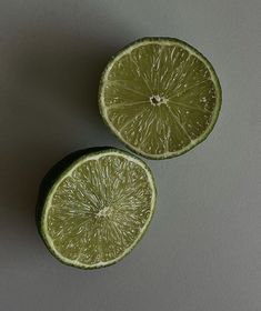 two limes cut in half on a gray surface