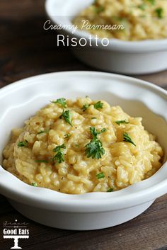 two white bowls filled with risotto on top of a wooden table