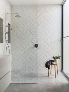 a walk in shower sitting next to a wooden stool