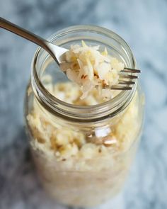 a spoon with some food in it on top of a glass jar filled with something