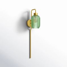 a green glass wall light on a white wall next to a gold pole with a bulb