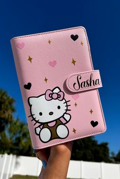 the hello kitty passport case is being held up by someone's hand with hearts and stars on it