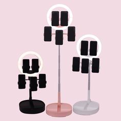 three different types of lights on stands against a light pink background, one with black square shapes and the other with white circles