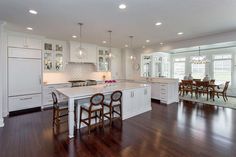 a large kitchen with white cabinets and wooden floors