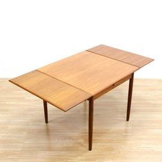 a wooden table sitting on top of a hard wood floor next to a white wall