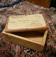 two wooden boxes with writing on them sitting on a carpeted floor next to a rug