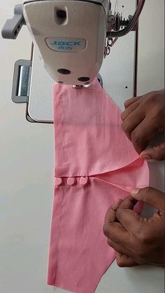 someone is using a sewing machine to sew pink fabric on a piece of cloth