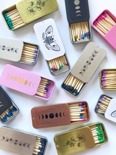 many different colored matches in tins on a white surface