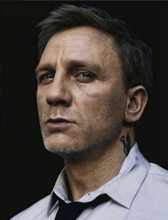 a man with a cross tattoo on his neck looking off to the side while wearing a white shirt and black tie