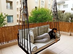 a young boy sitting on a swing bed in the middle of a rooftop garden area