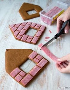 someone cutting out gingerbread shapes with a pair of scissors on a table next to them