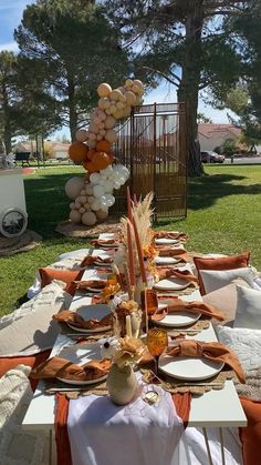 a long table set up with plates and orange napkins