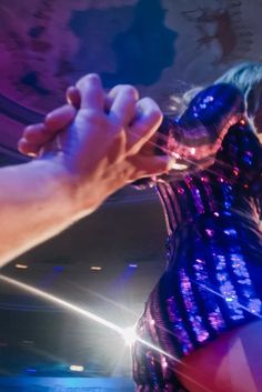 a woman in a sequined dress is holding her hand out to the crowd