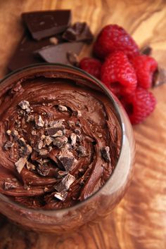 a chocolate dessert in a glass with raspberries on the side