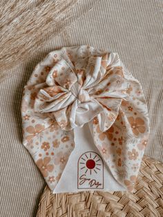 a close up of a hat on a bed with a woven bag in the background