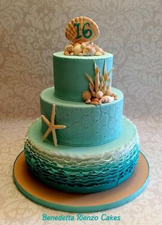 a three tiered cake decorated with sea shells and starfish on the top layer