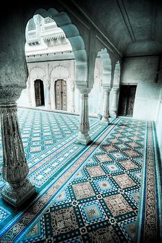 an intricately designed floor with columns and pillars in the middle, surrounded by blue tiles