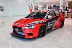 a red car is parked in a showroom