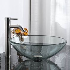 a glass bowl sink sitting on top of a black counter next to a faucet