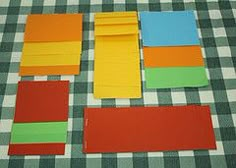 four pieces of colored paper laid out on a checkered tablecloth with scissors and tape