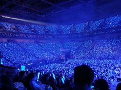 an audience at a concert with their cell phones in their hands and lights on the ceiling