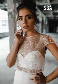 a beautiful young woman in a white dress posing for a magazine advertise with her hand on her chin