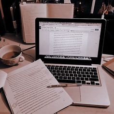 an open laptop computer sitting on top of a desk next to a cup of coffee