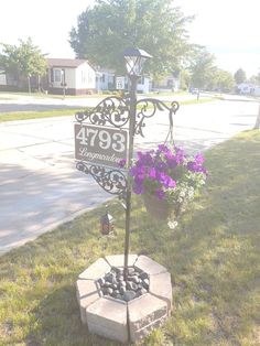 a street sign sitting on the side of a road next to flowers and potted plants