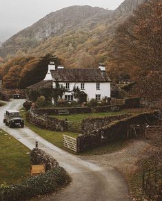 a car driving down a road next to a white house in the middle of mountains