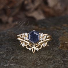 a gold ring with a blue stone surrounded by white diamonds on top of a rock