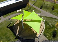 an aerial view of a large green umbrella in the middle of some grass and trees