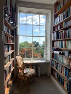 a chair sitting next to a window in a library filled with lots of book shelves