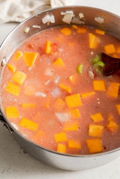 a pot filled with soup sitting on top of a counter next to a white towel