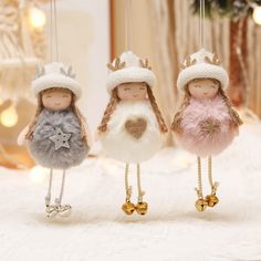 three little dolls wearing hats and dresses on a white surface with christmas lights in the background