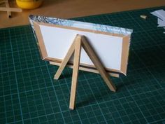 a wooden easel sitting on top of a green table next to a white board