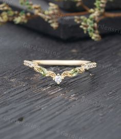 an image of a gold ring with green leaves on the side and diamonds in the middle