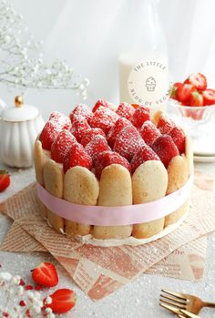 a cake with strawberries in the shape of hearts on top and pink ribbon around it