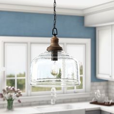 a kitchen light hanging from the ceiling over a sink and counter top in front of a window