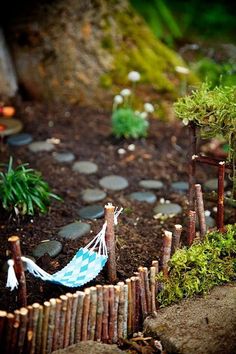 a miniature hammock in the middle of a garden with rocks and grass around it