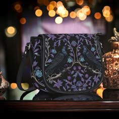 Gothic Violet Raven's Roost Vegan Cross-body Saddle Bag Purse.  🖤 Crafted with high quality vegan PU twill patterned leather, this gorgeous bag features a sleek metal clasp combined with a secure zipper closure for added convenience. Bag hardware is silver 🖤Luxe brown fabric interior, including one spacious main compartment, and a handy zipped pocket, this bag offers ample space for all your essentials. 🖤Equipped with an adjustable shoulder strap, offers the flexibility to be carried by hand Gothic Shoulder Bag For Everyday Use, Gothic Shoulder Bag For Alternative Fashion, Gothic Crossbody Shoulder Bag, Gothic Purse, Boho Witch, Saddle Bag Purse, Gothic Bag, Crossbody Handbags, Goth Girl