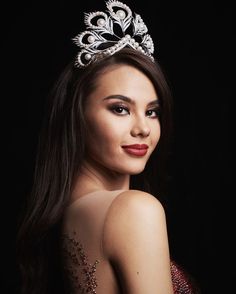 a beautiful woman wearing a tiara and posing for a photo in front of a black background