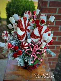 a vase filled with candy canes and candies on top of a wooden table