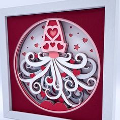 an ornament with hearts and a hat on it in a white box frame