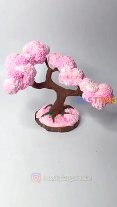 a bonsai tree made out of pink and white frosting on top of a wooden base