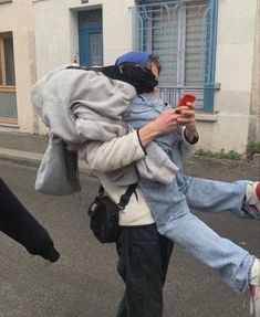 a man walking down the street while holding onto another person's leg and using a cell phone