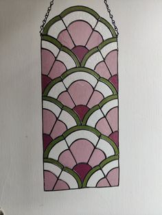 a stained glass window hanging from the side of a white wall with chains attached to it