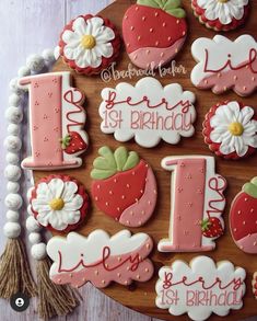 decorated cookies with the number one on them are displayed in front of a wooden board