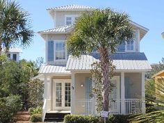 a white house with blue shutters and palm trees