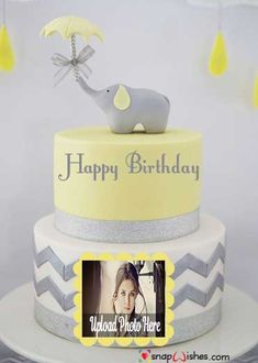 a yellow and gray birthday cake with an elephant topper on it's side